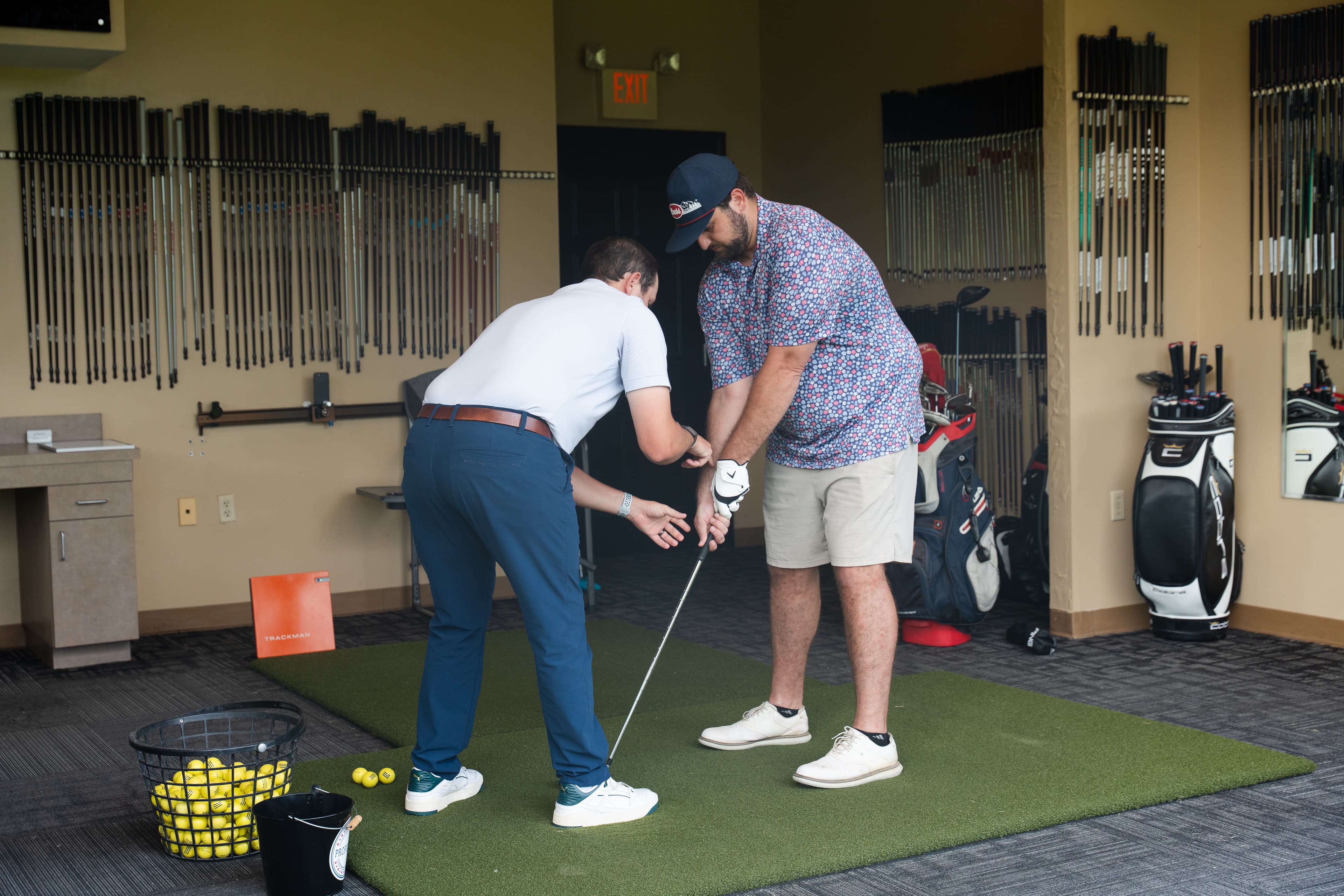A Profectus Golf coach helping a golfer adjust his grip during a lesson